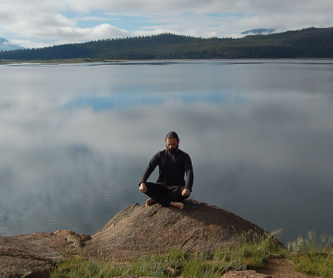 man meditating on a lake