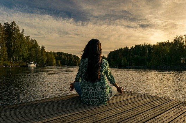 Woman sitting in meditation by a lake